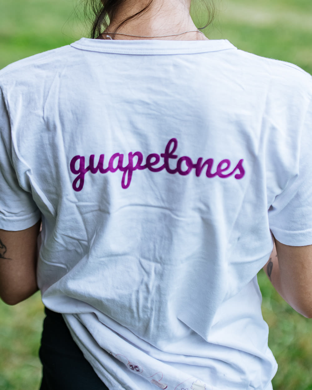 La espalda de una camiseta blanca con la palabra guapetones escrita a mano en violeta